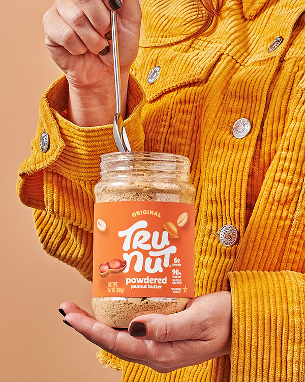 Hand holding a jar of TRU-NUT Powdered Peanut Butter